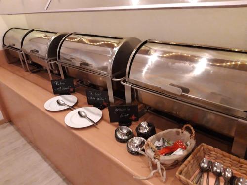 a buffet line with plates and utensils in a restaurant at Landhaus Pfahlershof in Karolinenkoog