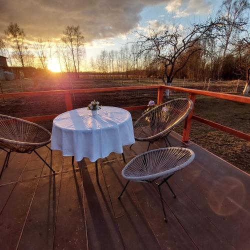 - une table et deux chaises sur une terrasse avec vue sur le coucher du soleil dans l'établissement DebessJums, à Nereta