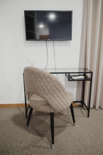 a chair and a table with a television on a wall at Alojamento 88 in Castro Daire
