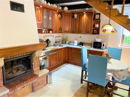 a kitchen with a fireplace and a table with chairs at Kuća Homer in Mala Lešnica