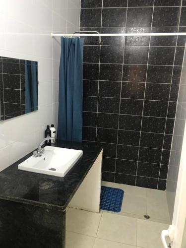 baño de azulejos negros con lavabo y ducha en La Bella BedoUina, en Wadi Musa
