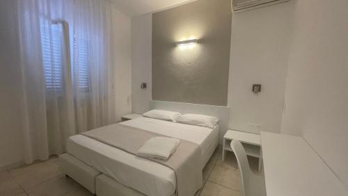 a small white room with a bed and a mirror at Hotel L'Ogliera in Pomonte