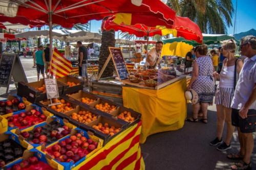 Un groupe de personnes autour d'un stand de fruits sur un marché dans l'établissement Agréable maison au cœur du village, à Argelès-sur-Mer
