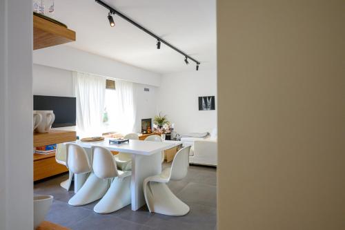 a white dining room with a white table and chairs at 5 meters from the beach in Chrani