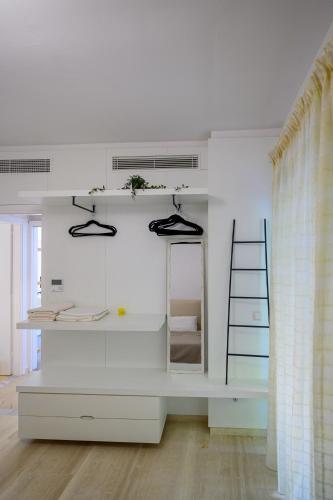 a room with a white wall with shelves and a mirror at 5 meters from the beach in Chrani