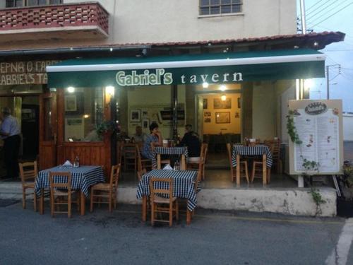a restaurant with tables and chairs in front of a building at 2 Palaepaphos Gardens in Kouklia