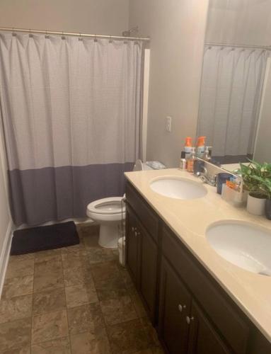 a bathroom with two sinks and a toilet with a shower at Private, quiet, immaculate bachelor pad with free parking on site in Decatur