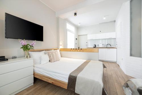 a white bedroom with a large bed with a flat screen tv at Apartamenty Baltic in Sopot