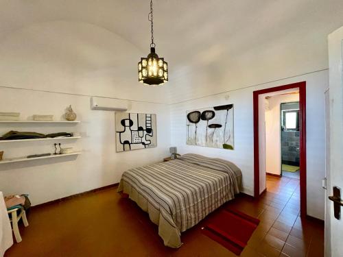 Schlafzimmer mit einem Bett und einem Kronleuchter in der Unterkunft Dammuso "La Catalana" in Pantelleria