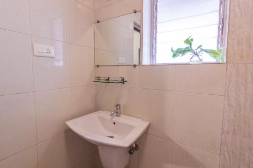 a white bathroom with a sink and a window at Villa Candolim in Candolim