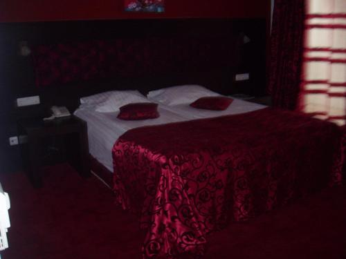 a bedroom with a bed with red sheets and pillows at Hotel Sydney in Craiova