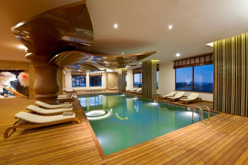 a pool in a house with chairs and a table at Kaya Palazzo Ski & Mountain Resort in Kartalkaya