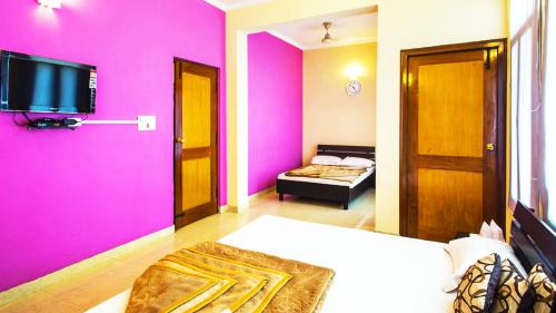 a bedroom with pink walls and a tv on the wall at Shivalik River Retreat in Almora