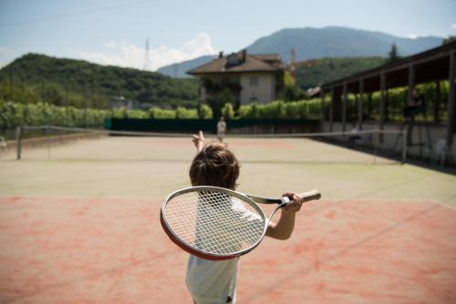 a child holding a tennis racket on a tennis court at Hotel Frangart an der Weinstraße in Appiano sulla Strada del Vino
