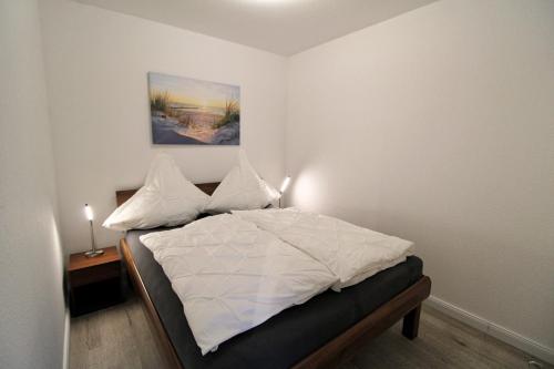 una camera da letto con letto, lenzuola e cuscini bianchi di Strandoase - a68194 a Cuxhaven
