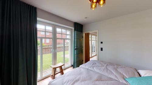 a bedroom with a bed and a large window at Landhaus Lindenhof, Insel-Juwel in Wangerooge