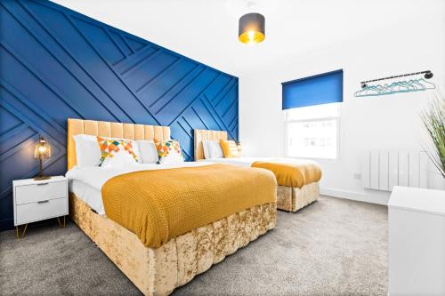 a bedroom with two beds and a blue wall at Stylish 2BR Apartment in Morriston in Swansea