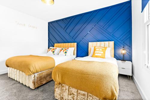 two beds in a room with a blue wall at Stylish 2BR Apartment in Morriston in Swansea