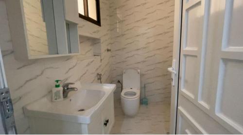 a white bathroom with a sink and a toilet at Al Jabal Resort Villa 3 in Salalah