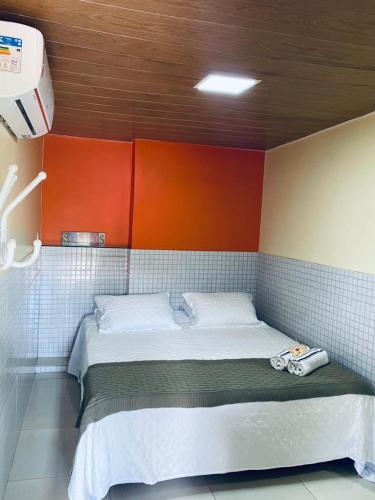 a small bed in a room with orange and blue at Casa Da Didda in Fernando de Noronha