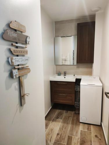 La petite salle de bains est pourvue d'un évier et d'un réfrigérateur blanc. dans l'établissement LENIE appartement reposant, à Lanester