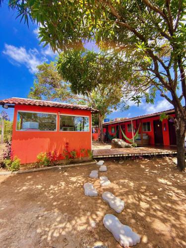 une maison rouge avec des rochers devant elle dans l'établissement Casa Da Didda, à Fernando de Noronha