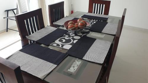 a dining room table with four chairs and a bowl of fruit at Rodrigo Apartments 3 in Boralesgamuwa
