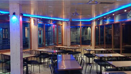a restaurant with tables and chairs and blue lights at Shivalik River Retreat in Almora