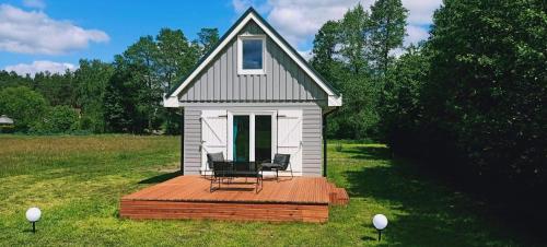a tiny house with two chairs on a wooden deck at Nowy Domek na Mazurach - łowisko ryb in Szczytno