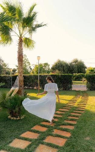 a woman in a white dress walking on a brick path at B&B Villa Mamma Grazia in San Vito dei Normanni