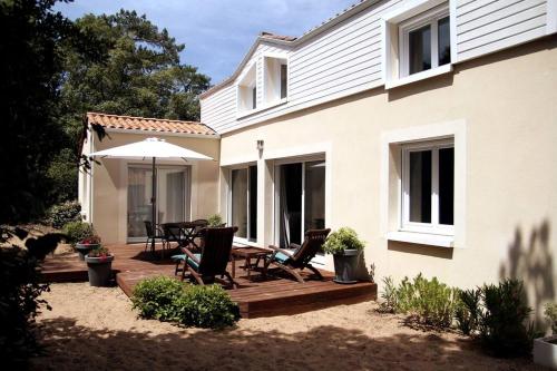 une maison dotée d'une terrasse en bois avec des chaises et un parasol dans l'établissement BUD HOUSE MAGNIFIQUE VILLA PROCHE DE LA MER, à Longeville-sur-Mer