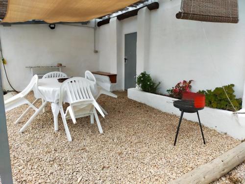 a patio with white chairs and a table and a grill at Estudio "La Cochera de Sorrapa" in Deltebre