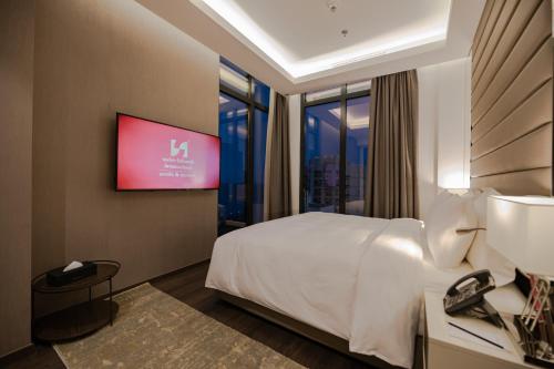 a hotel room with a bed and a flat screen tv at Swiss-Belboutique Bneid Al Gar Kuwait in Kuwait