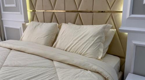Una cama con sábanas blancas y almohadas. en Al Jabal Resort Villa 4, en Salalah