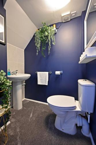 a blue bathroom with a toilet and a sink at Central Townhouse with FREE onsite EV parking in Stratford-upon-Avon