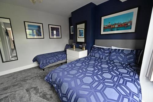 Un dormitorio con dos camas y una pared azul. en Central Townhouse with FREE onsite EV parking, en Stratford-upon-Avon