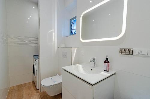 a white bathroom with a sink and a toilet at Suartini Apartmani Račišće in Račišće