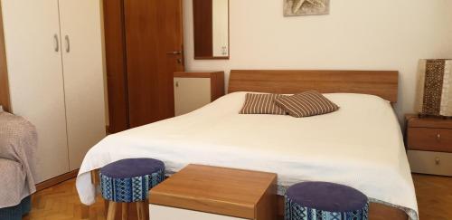 a bedroom with a bed with two purple stools at Pende in Banjol