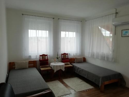 エゲルサロークにあるVadásztanya Fogadóのベッド2台、テーブル、窓が備わる客室です。