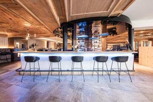 a bar with four stools in a room at DAS GERSTL Alpine Retreat in Malles Venosta