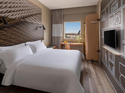 a hotel room with a bed and a television at Ibis Jeddah Malik Road in Jeddah
