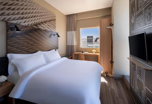 a bedroom with a large white bed and a flat screen tv at Ibis Jeddah Malik Road in Jeddah