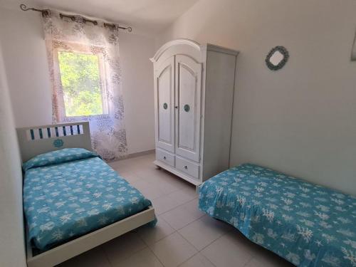 a bedroom with two beds and a cabinet and a window at Casa Vacanza Boi-Dessena in Cala Liberotto