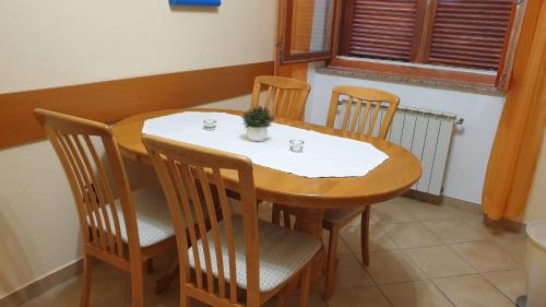 een houten tafel met vier stoelen en een tafel met een plant erop bij GABY apartment-center of Plitvička Jezera in Plitvička Jezera
