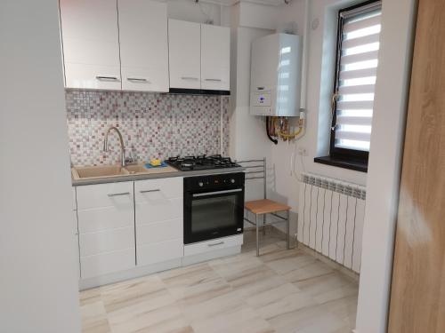 a kitchen with white cabinets and a stove and a sink at BYA BROWN in Valea Lupului
