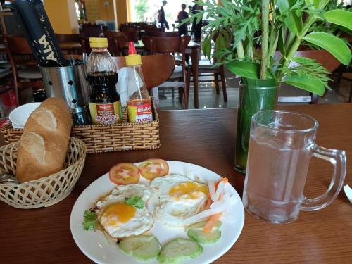 a plate of eggs and tomatoes and a glass of water at Khách sạn Vườn Cau & Khu vui chơi giải trí SaLa in Tây Ninh