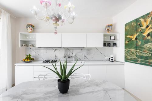 a white kitchen with a potted plant on a table at Panarea 22 in Calabernardo