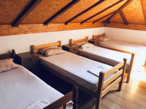 three beds in a room with wooden ceilings at Vikendica Atos in Nova Topola