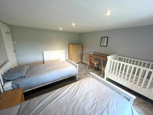 a bedroom with two beds and a desk at Pass the Keys Spacious 3BR Cottage in Beautiful Rural Setting in Castle Douglas
