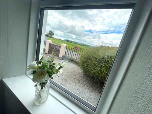 a window with a vase of flowers on a table at Pass the Keys Spacious 3BR Cottage in Beautiful Rural Setting in Castle Douglas